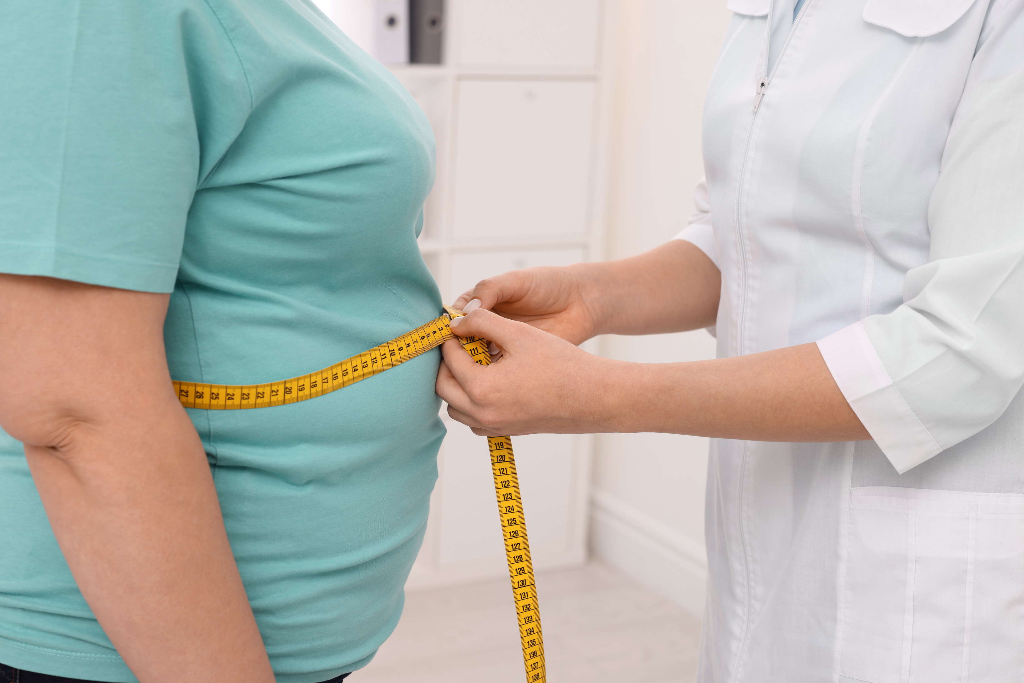 Nutritionist Measuring  Woman's Waist with Tape in Cli