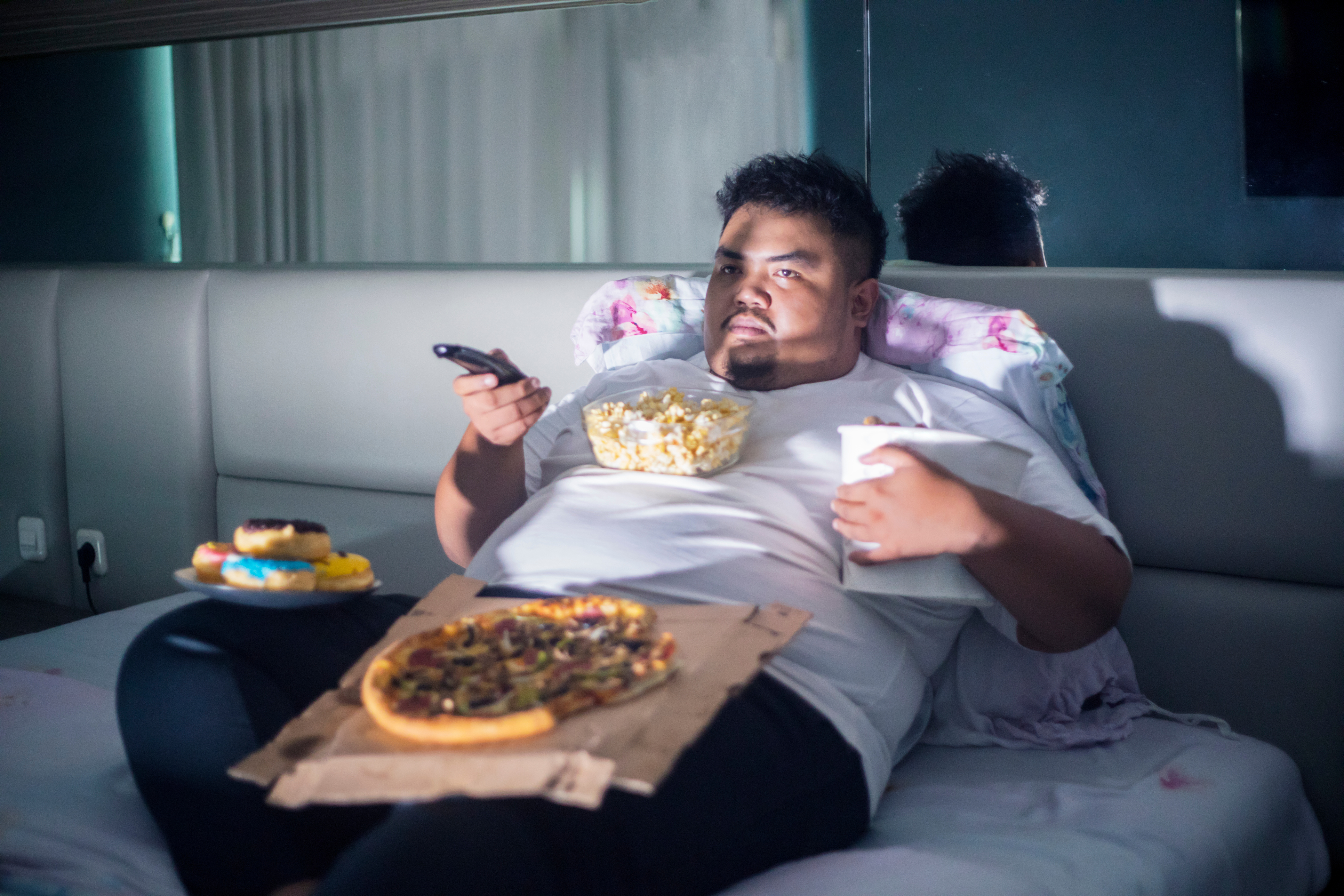 Plus Size Man Eating Junk Food on the Bed